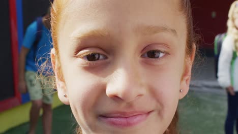 Portrait-of-happy-caucasian-schoolgirl-looking-at-camera-on-playground