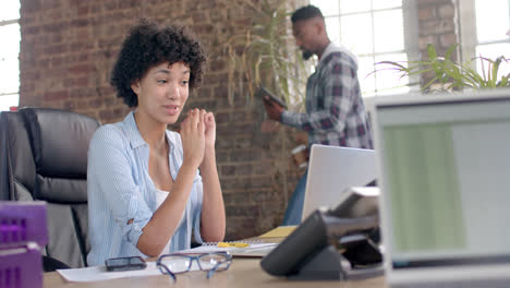 focused diverse colleagues using tablet and having laptop video call in office in slow motion