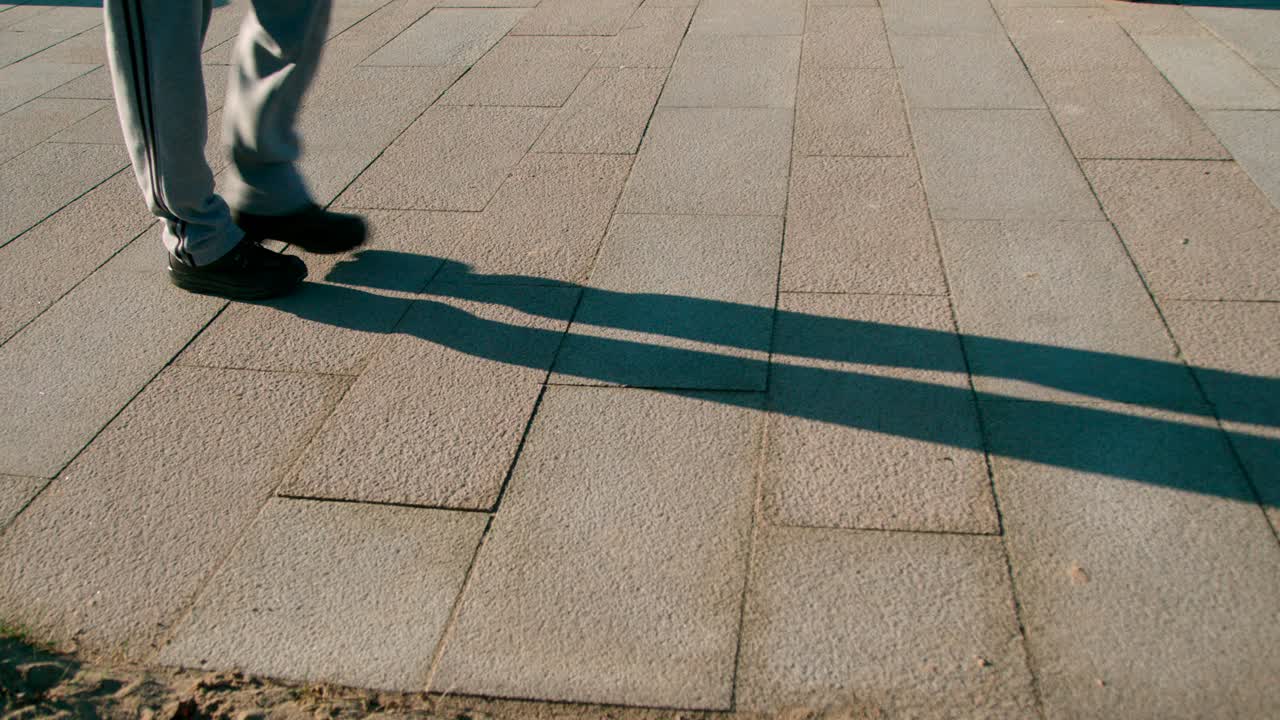 un hombre caminando lentamente en un parque en un brillante amanecer - plano medio