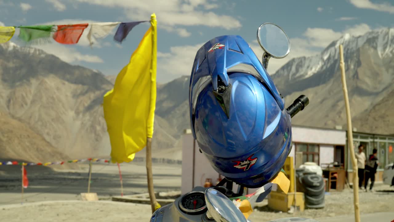 Detailed closeup of blue motorcycle helmet with mountains and Buddhist Prayer flags in Himalayas in Ladakh, India
