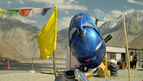 detailed closeup of blue motorcycle helmet with mountains and buddhist prayer flags in himalayas in ladakh, india