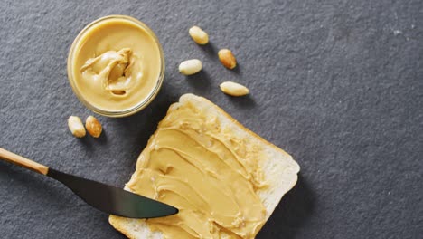 Video-of-close-up-of-toast-with-peanut-butter-on-gray-background