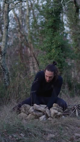 Man Meditating by Rock Pile in Forest