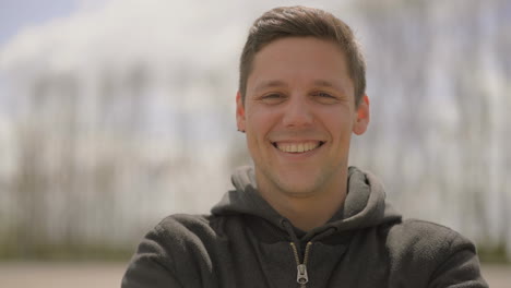 young man laughing and looking at camera outdoor