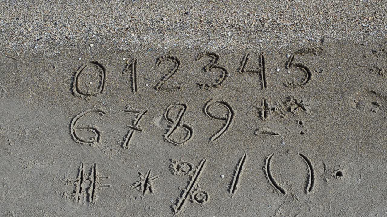 Cijfers en tekens geschreven in strandzand. Strandopname.