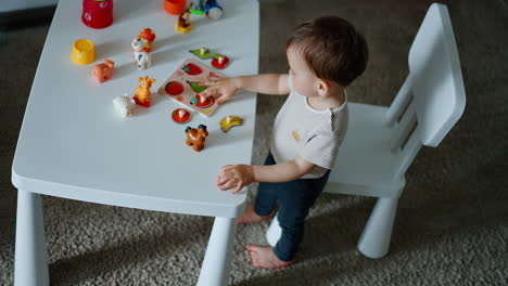 infant boy learning fruit through the game. baby plays with toys at the desk. top view perspective.