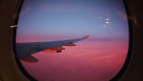 Blick-Aus-Dem-Flugzeugfenster-über-Rosafarbenen-Wolken