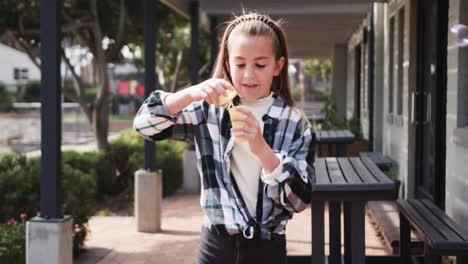 girl blowing bubbles outdoors, enjoying playful moment at school courtyard