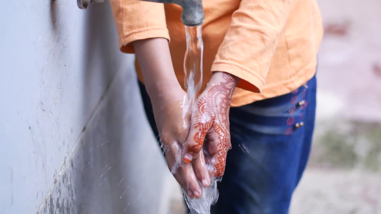 niño lavando las manos en un grifo de agua