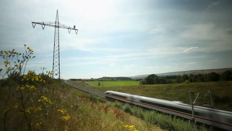 high-speed electric passenger train passing through valley with flowers in frankfurt, germany