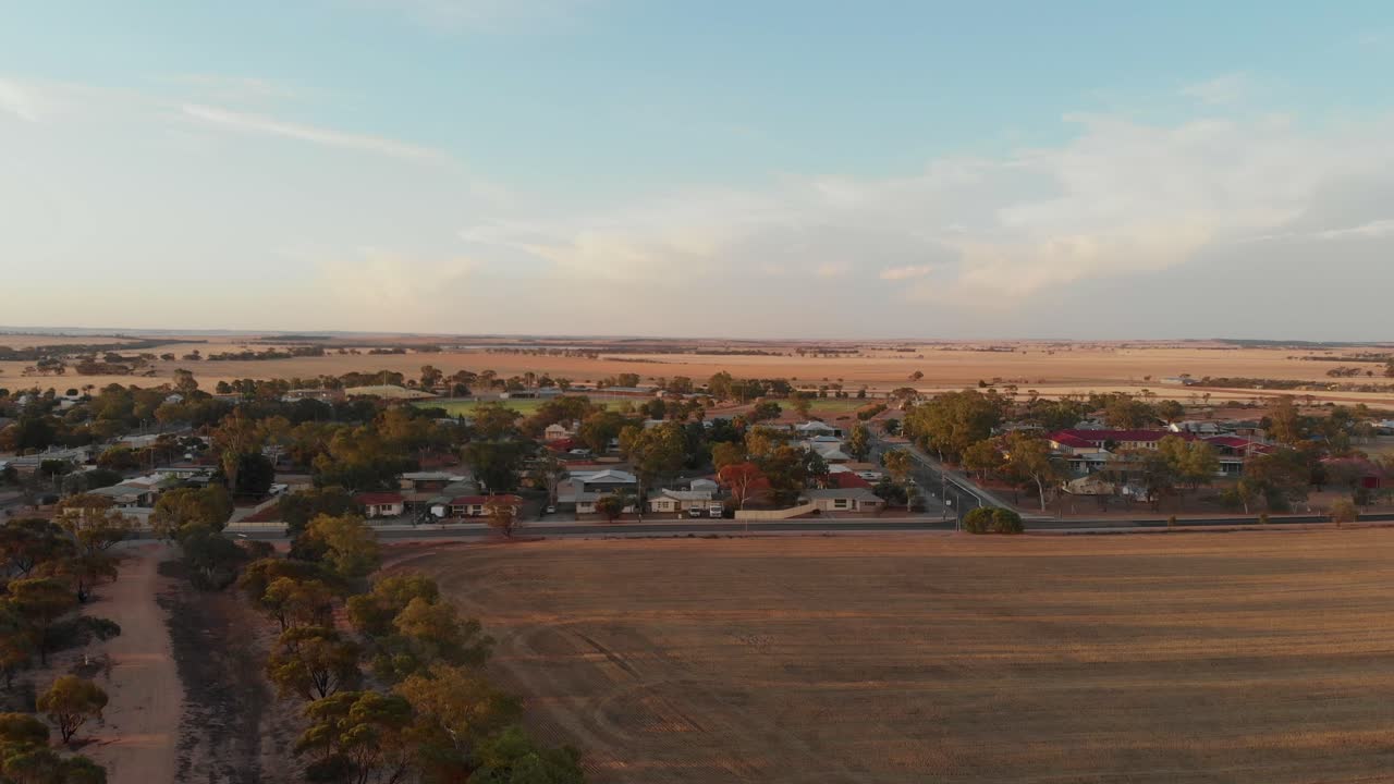 Vista aerea di un tranquillo villaggio nell'outback e della strada che risplendono all'alba a Carnamah, Australia Occidentale