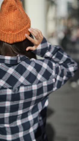 stylish woman in orange beanie and plaid shirt