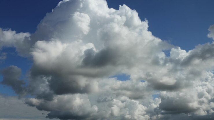 Dramatic slow cumulus cloud formations coming up passing by and diminishing against a blue sky