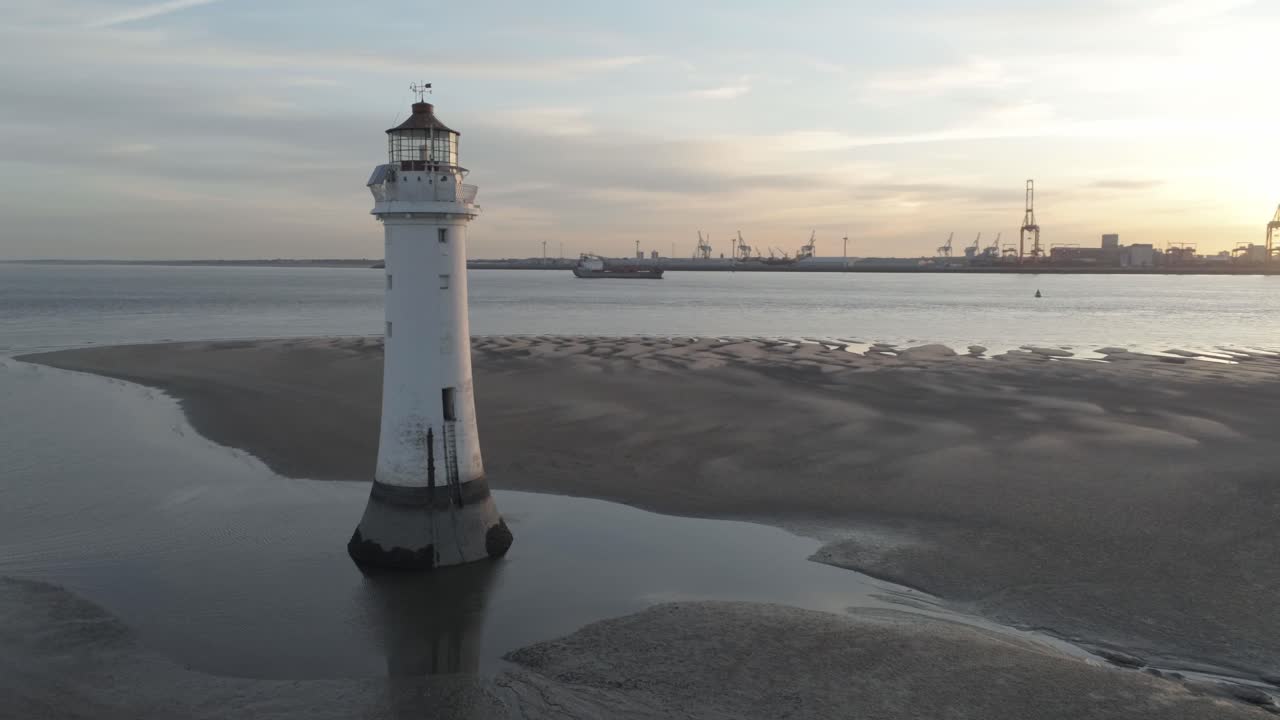 vista aérea derecha de órbita lenta a través del faro británico y grúas de astillero costero amanecer horizonte