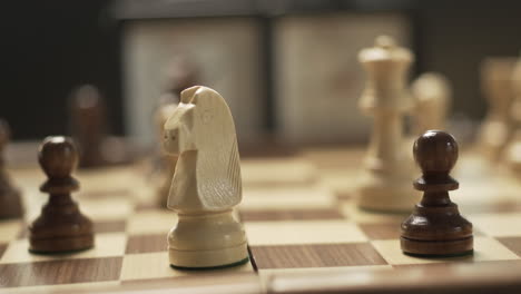 woman playing chess in close-up, female hand with shiny nail polish moving the knight, making check