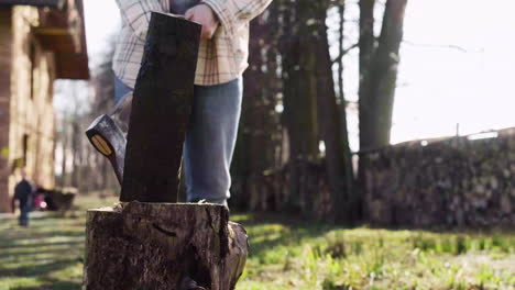 bottom view of caucasian man chopping firewood with an ax outside a country house. then he looks at camera