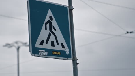 signo de carretera para peatones que cruzan en el clima nublado de fondo de la ciudad.