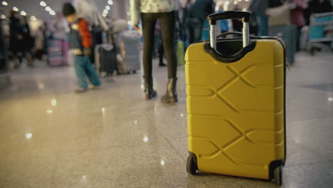 yellow suitcase on the floor at crowded airport