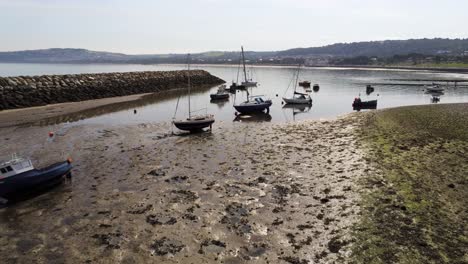 Aerial-view-boats-in-shimmering-low-tide-sunny-warm-Rhos-on-Sea-seaside-sand-beach-marina-low-push-in-forward-above-masts