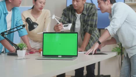 아시아 엔지니어 그룹이 사무실에서 풍력 터빈에 대한 회의를 하는 동안 녹색 스크린 노트북이 테이블 위에 있습니다.