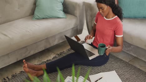 Video-of-happy-african-american-woman-sitting-on-floor-using-laptop