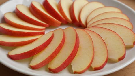 a beautiful arrangement of fresh apple slices showcasing their crisp texture and vibrant red skin on a white plate, perfect for healthy snacking or garnishing dishes