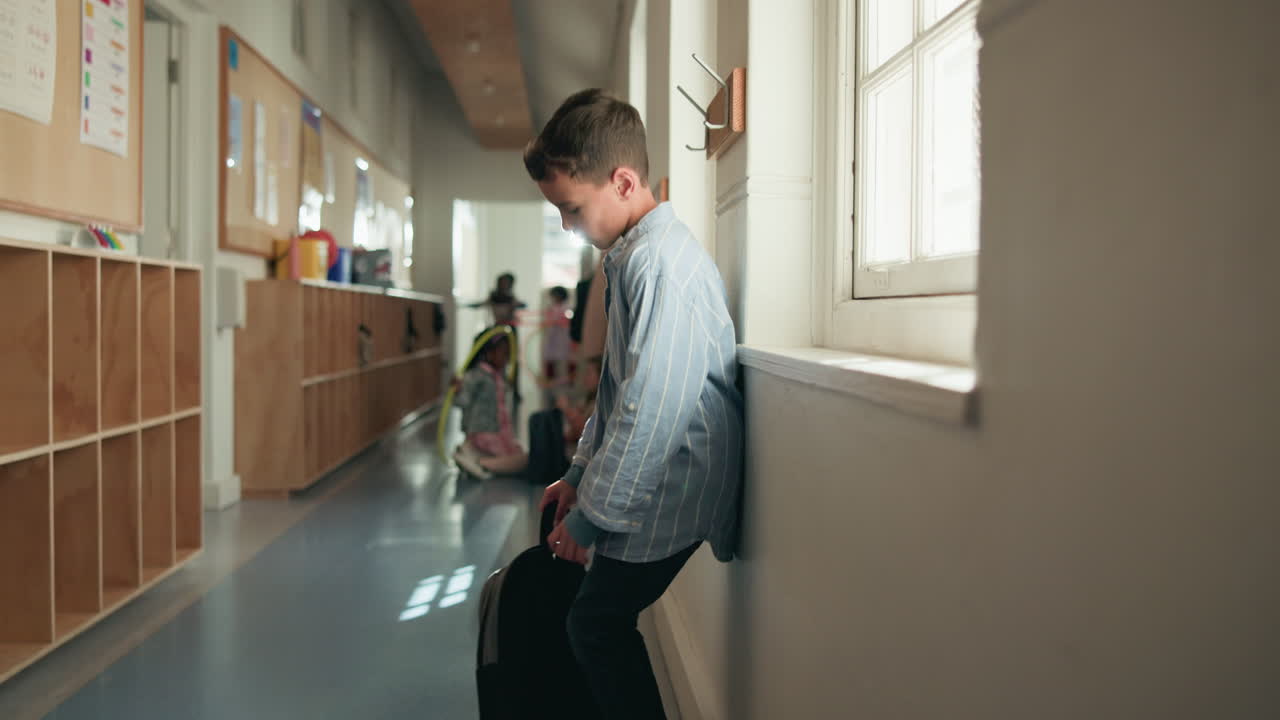Sad and lonely child sitting alone in a school hallway