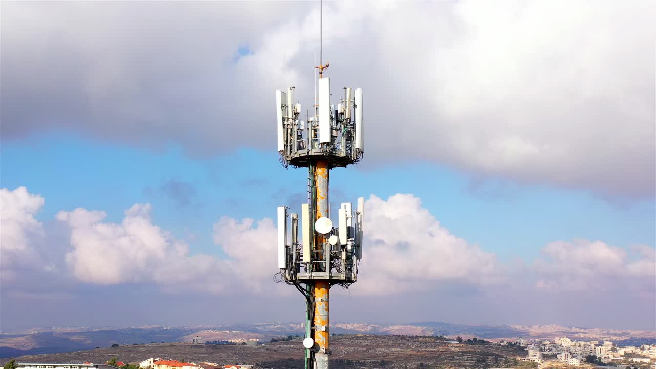 Cell Tower with Cloudy Sky and Cityscape