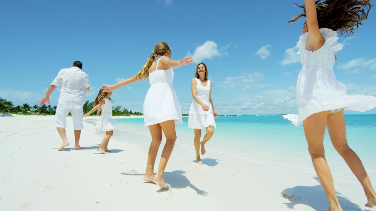 Happy Caucasian family walking on a tropical beach