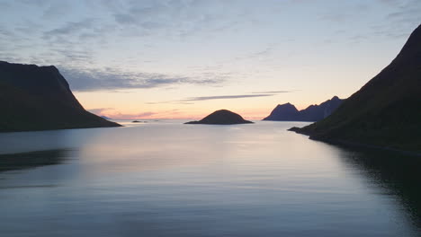Wunderschöner-Gelber-Und-Blauer-Sonnenuntergang-über-Idyllischem-Meerwasser-Und-Silhouetten-Von-Bergen,-Luftaufnahmen