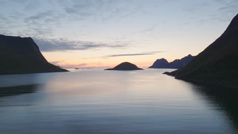 beautiful yellow and blue sunset over idyllic ocean water and silhouettes of mountains, aerial