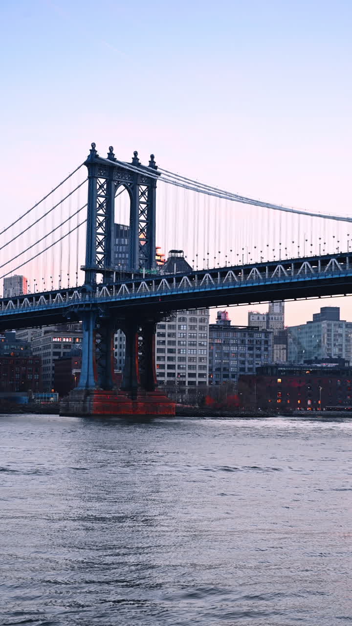 Beautiful Manhattan Bridge at sunset time. Low angle view at the famous landmark from the riverscape. Vertical video