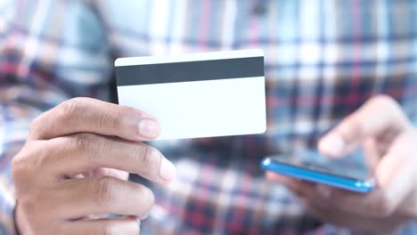 person holding a credit card and using a mobile phone for online payment