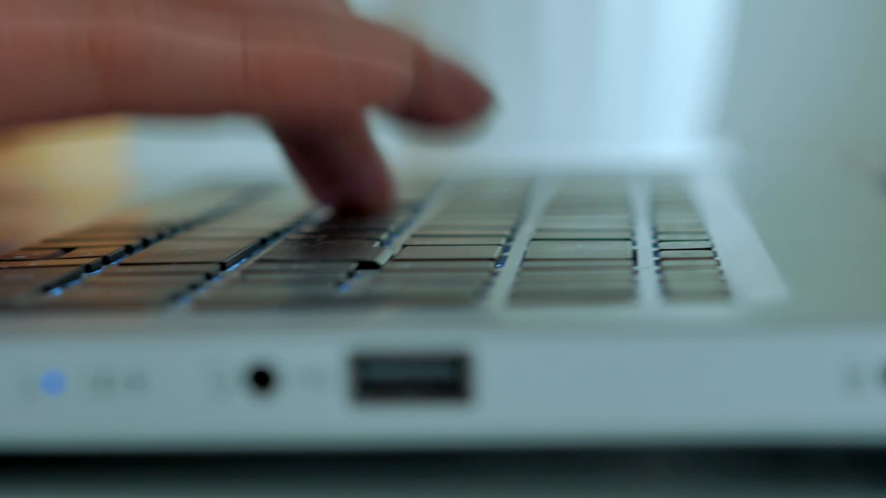 A close -up, male hands hit the keyboard of a laptop, print a text, a selective focus
