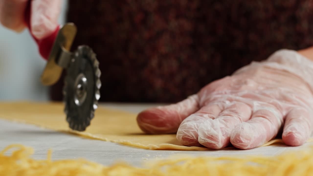 Close-Up of Hands Cutting Fresh Pasta Dough with a Pastry Wheel