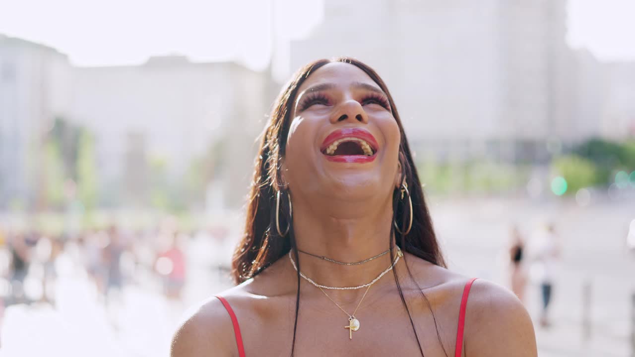 A joyful person smiling and laughing in an urban outdoor setting