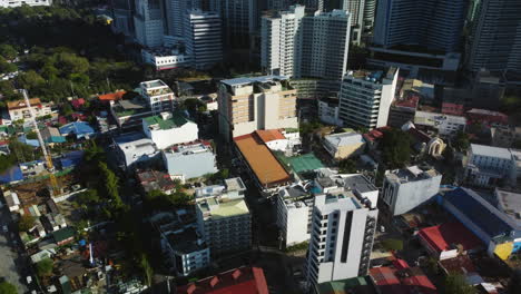 Aerial-view-tilting-over-modern-condos,-toward-the-Makati-skyline,-sunny-Philippines