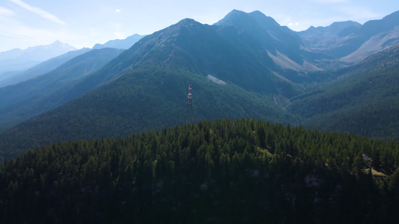 drone disparado volando alrededor de una columna de alto voltaje de pie en la cima de una gran colina en los alpes italianos