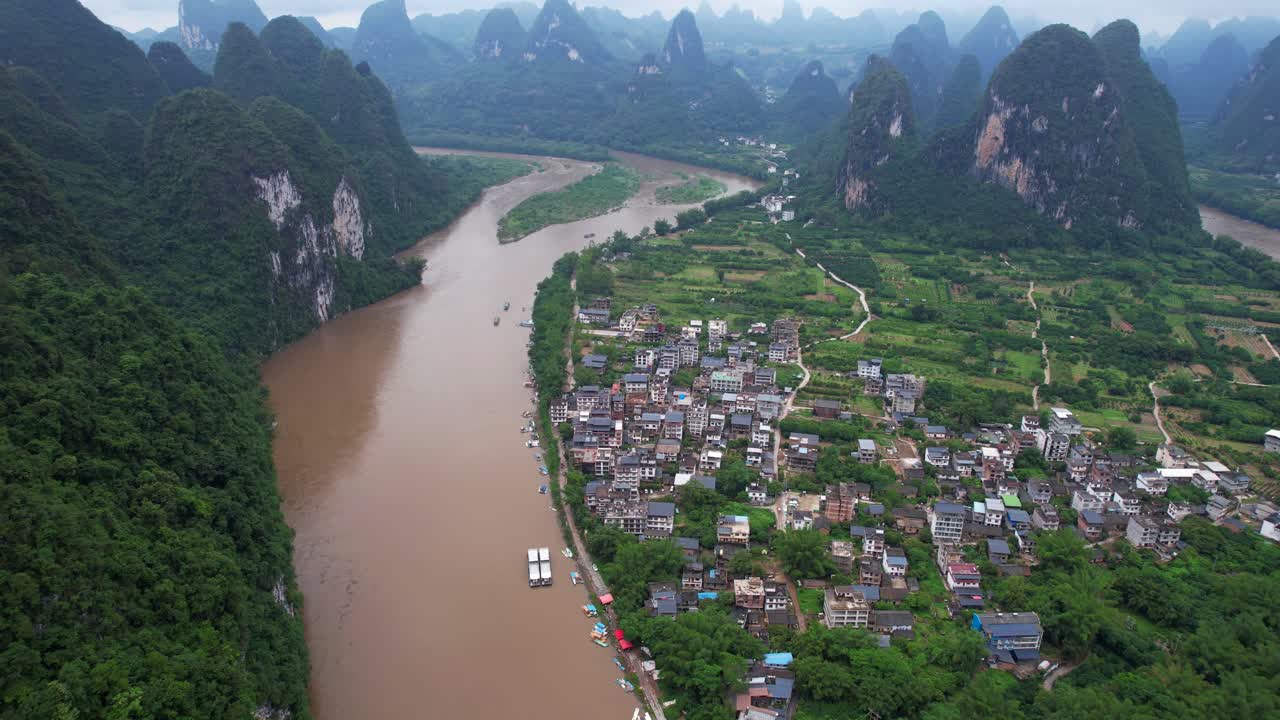 tomada aérea de la antigua ciudad de xingping junto al río li con un paisaje montañoso cárstico en el fondo, china