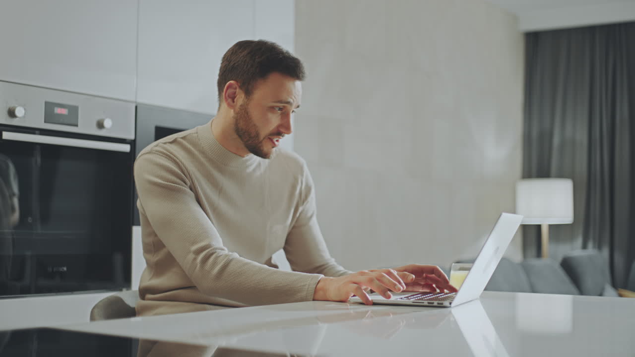 hombre trabajando en una computadora portátil en la cocina