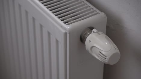 hand turning radiator or heating thermostat off, saving money during economics crisis