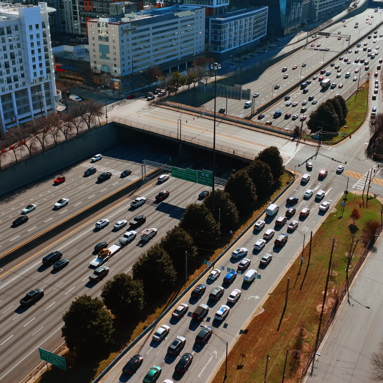 Numerous cars run by the multilane road in downtown of Atlanta on daytime. Sunny panorama of the city from top.