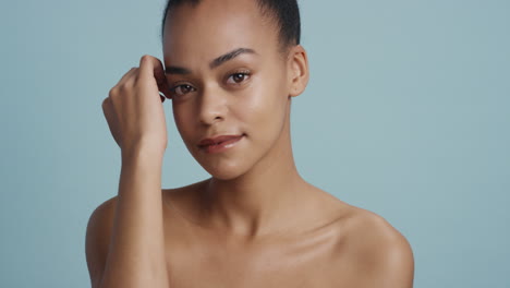 Retrato-Hermosa-Mujer-Afroamericana-Tocando-El-Cuerpo-Con-La-Mano-Acariciando-Una-Tez-De-Piel-Suave-Y-Saludable-Disfrutando-De-Una-Belleza-Natural-Perfecta-Luciendo-Confiada-En-El-Concepto-De-Cuidado-De-La-Piel-De-Fondo-Azul