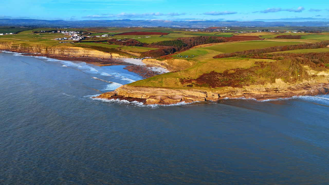 Vista aerea del promontorio e della costa a Dunraven Bay. Ampia ripresa con drone del promontorio roccioso e della spiaggia sabbiosa a Southerndown sotto la luce del giorno.