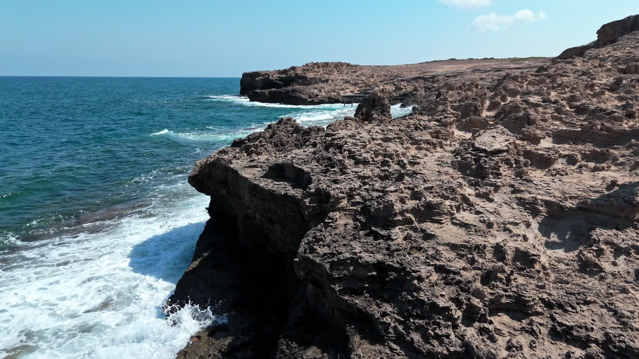 Rocky coastline with waves crashing against cliffs on the north coast of Cyprus on a sunny day
