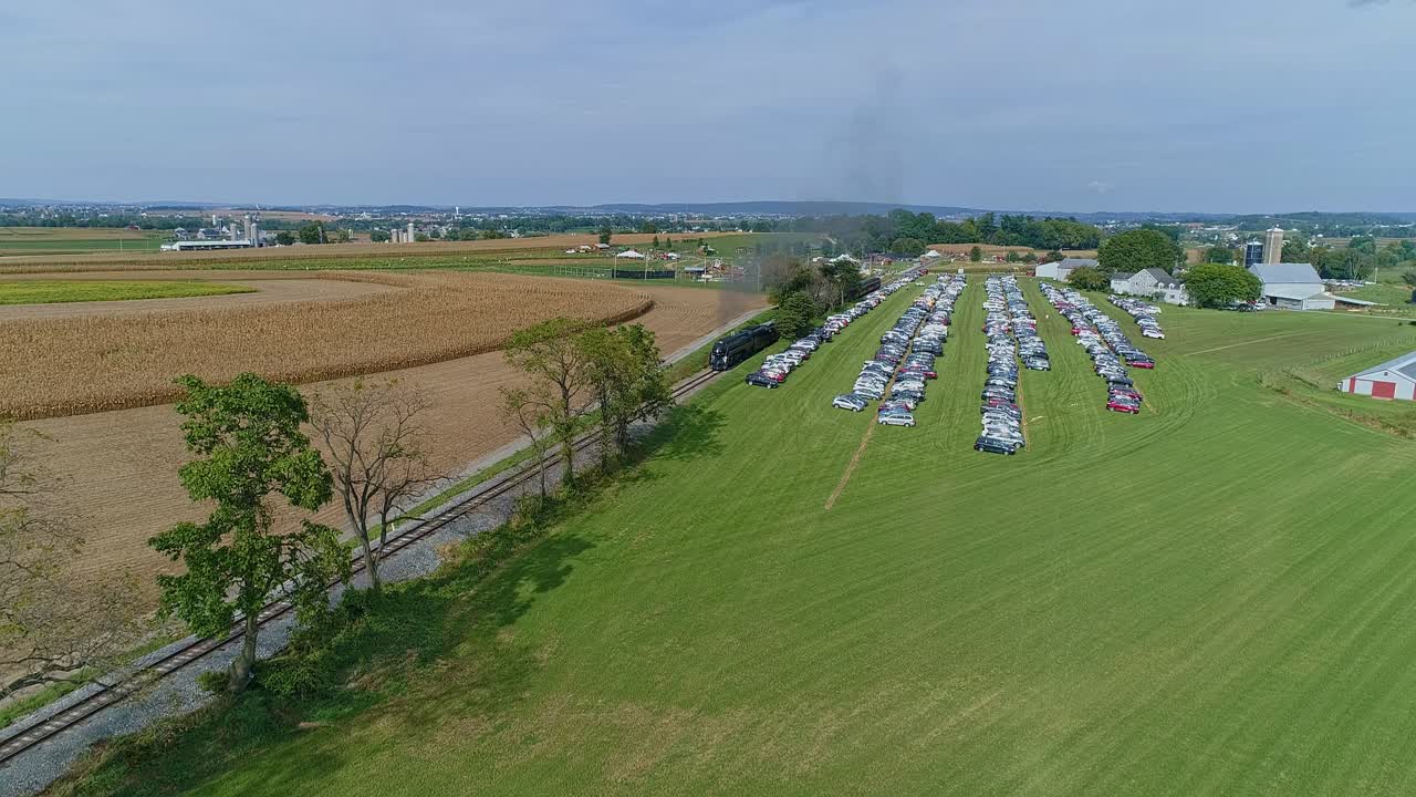 화창한 가을날 비옥한 옥수수 밭을 가로질러 연기와 증기를 내뿜으며 접근하는 골동품 증기 여객 열차의 공중 전망