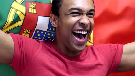 fanático portugués celebrando mientras sostiene la bandera de portugal en cámara lenta