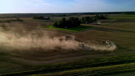 aerial view of combine harvesters dusting on a field, fall day on the countryside