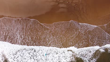 Atemberaubende-Luftaufnahme-Von-Surfern-Und-Wellen,-Die-Am-Langen-Sandstrand-Von-Tynemouth-Zusammenbrechen