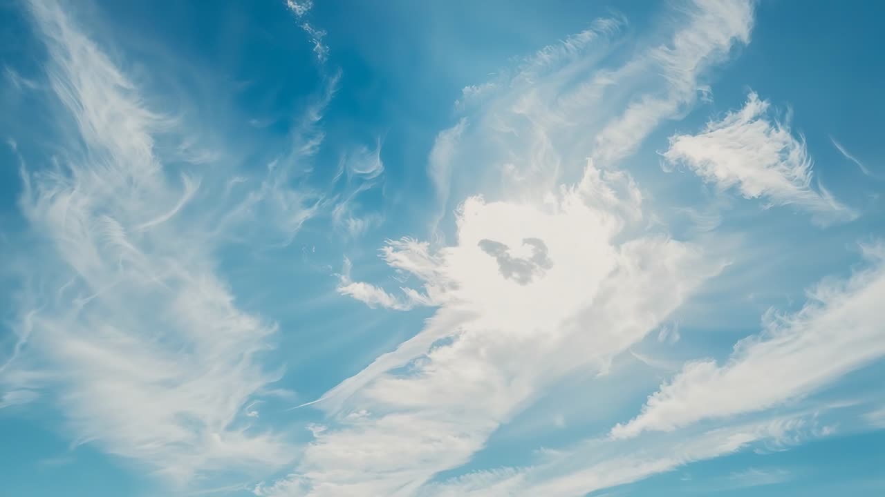 Sunlight peeking behind cloud swirl with cirrus clouds drifting in open sky revealing blue expanse